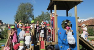 Die Kinder der Kita Farbenland stehen und klettern auf dem Klettergerüst und winken.