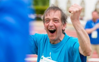 Porträt eines Teilnehmers bei den Special Olympics der jubelnd die Fäuste hochhebt.