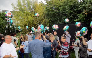 Besucher des Sommerfests der Lebenshilfe Neuss, die Luftballons in den Händen halten.