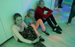 Drei Kinder die eine U-16 party im Kinder- und Jugendzentrum besuchen in buntem Disko-Licht.