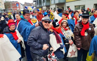 Nutzer und Mitarbeitende der Lebenshilfe Neuss auf dem Kappessonntagszug in bunten Karnevalsverkleidungen.