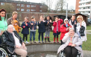 Gruppenfoto von Bewohnerinnen aus dem Seniorenheim Curanum mit drei Begleitungen zu Besuch im Familienzentrum am Baldhof, geimsam mit Kindern und Mitarbeitenden des Familienzentrums.