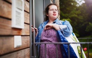 Eine junge Frau mit einer Behinderung die verträumt aus dem Bild guckt.