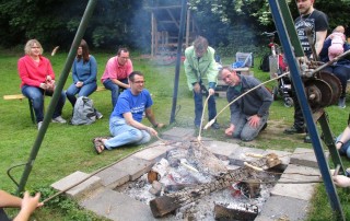 Nutzer und MItarbeiter der Lebenshilfe Neuss machen Stockbrot an einer großen Feuerstelle.