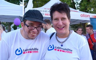 Die Geschäftsführerin der Lebenshilfe Neuss und ein Nutzer, beide in weißen T-Shirts der Lebenshilfe Neuss, beim Firmenlauf.