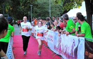 Eine Teilnehmerin und ein Teilnehmer der Lebenshilfe Neuss laufen zwischen Zuschauern beim Firmenlauf auf das Ziel zu.