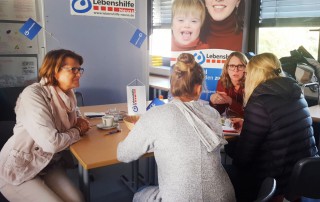 Mitarbeiterinnen und Bescuherinnen der Berufsinformationsmesse im Marienhaus sitzen am Stand der Lebenshilfe Neuss.