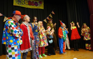 Bunt verkleidete Menschen auf der Bühne beim Karneval.