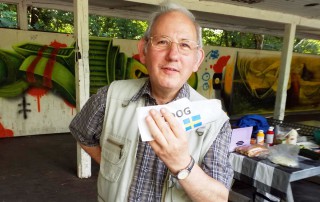 Porträt eines älteren UWO-Nutzers der einen Hot-Dog in der Hand hält.