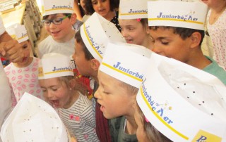 Eine Gruppe Kinder mit Bäcker-Mützen auf den Köpfen.