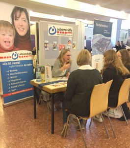 Auf der Berufsinformationsmesse im Marienhaus sitzt eine Mitarbeiterin mit zwei Besucherinnen am Stand der Lebenshilfe Neuss.