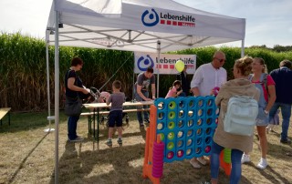 Mitarbeitende und Besucher stehen am Stand der Lebenshilfe Neuss.