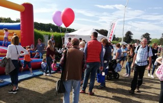 Eine Hüpfburg und Besucher auf dem Familienfest im Dycker Feld.