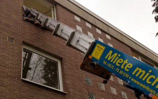 Ein Kran befördert Gegenstände in und aus einer Wohnung oben in einem Haus bei einem Umzug.