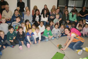 Eine große Gruppe Kinder und Mitarbeitende sieht eine Aufführung an.