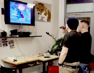 Zwei junge Männer stehen vor einem Bildschirm und singen Karaoke.