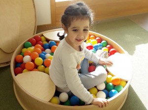 Ein Mädchen sitzt in einem kleinen Bälle-Bad.