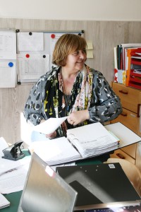 Eine Mitarbeiterin am Schreibtisch die etwas in einen Ordner einheftet.