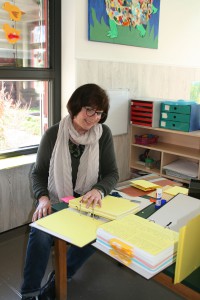 Eine Mitarbeiterin sitzt vor vielen Dokumenten und Akten am Schreibtisch.