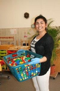 Eine Mitarbeiterin trägt einen Wäschekorb voller Duplosteine.