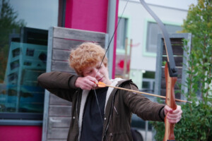 Ein Junge schießt mit Pfeil und Bogen.