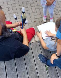 Ein Mitarbeiter des KiJuZes bereitet mit den Kindern draußen die Arbeiten für das Häuschen vor.