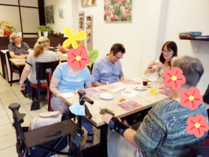 Die Besucher des Crazy Fridays sitzen im Lebenshilfe Center der Lebenshilfe Neuss und spielen Bingo.