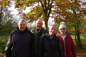 Der Ehrenamtler und mehrere zu betreuende Personen stehen zusammen für ein Gruppenfoto.