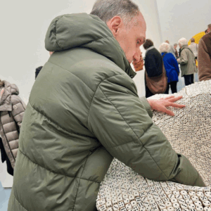 Ein Bewohner bestaunt ein Kunstwerk und berührt es mit der Hand.