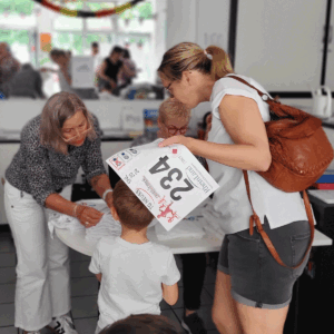 Ein Kind bekommt von einer Frau seine Start-Nummer.