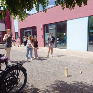 Mehrere Kinder spielen draußen mit einer Erzieherin.