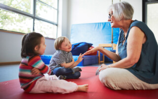 Eine Frau spielt mit zwei Kindern auf dem Boden