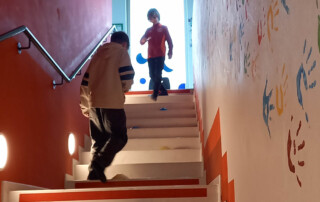 Zwei Kinder spielen Eier-Laufen auf einer Treppe.