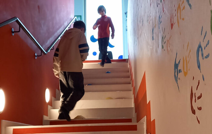 Zwei Kinder spielen Eier-Laufen auf einer Treppe.