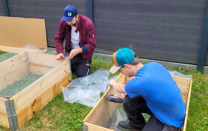 Zwei Väter bauen zusammen zwei Hoch-Beete-Kästen auf.