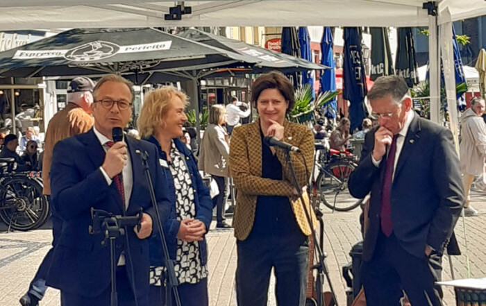 Vier Personen stehen an einem Mikrofon