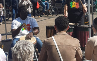 Ein Mann und eine Frau spielen auf afrikanischen Trommeln auf einem Stadt-Fest.