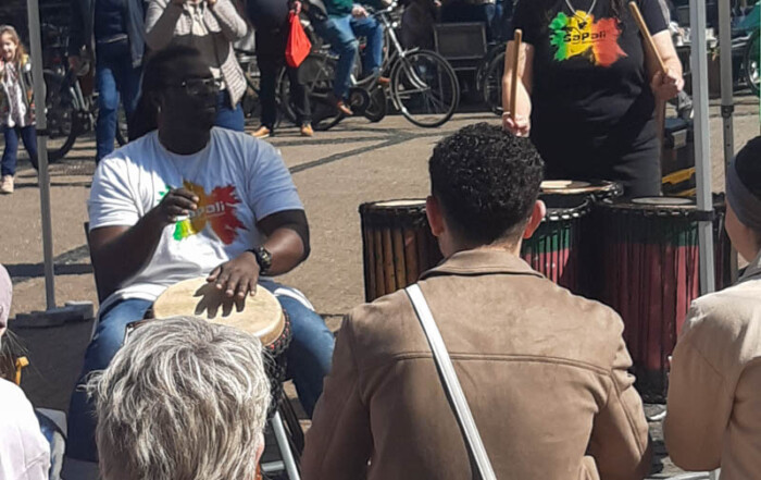 Ein Mann und eine Frau spielen auf afrikanischen Trommeln auf einem Stadt-Fest.