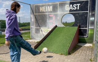 Eine Teilnehmerin schießt einen Ball durch ein Fußball-Golf Tor.