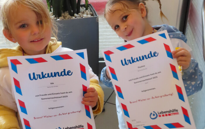Zwei kleine Mädchen halten ihre Teilnahme-Urkunden vom Sommernachtslauf 2025 hoch.
