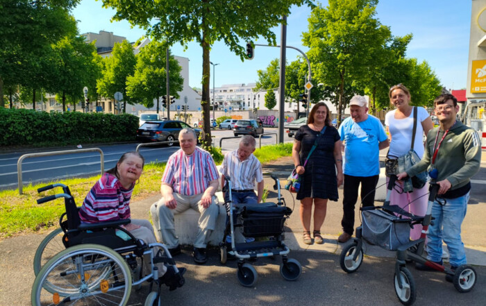 Mehrere Personen stehen draußen an einer Straße zusammen für ein Gruppenfoto.