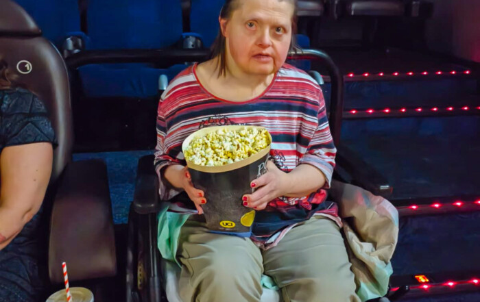 Eine Frau sitzt mit Popcorn in der Hand im Kinosaal.