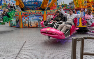 Zwei Bewohner fahren auf einem Fahrgeschäft und ein Bewohner zeigt dabei das Peace-Zeichen mit den Fingern.