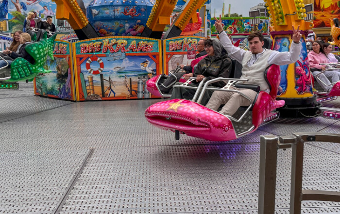 Zwei Bewohner fahren auf einem Fahrgeschäft und ein Bewohner zeigt dabei das Peace-Zeichen mit den Fingern.