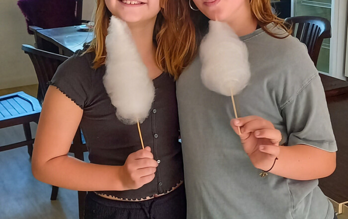 Zwei Mädchen schauen in die Kamera und essen Zuckerwatte.