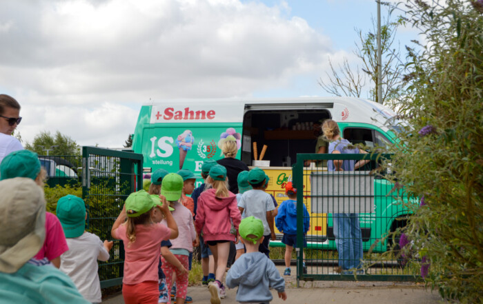 Mehrere Kinder stehen Schlange vor dem Eiswagen.