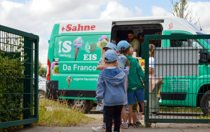 Mehrere Kinder stehen Schlange vor dem Eiswagen.