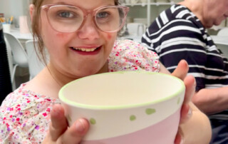 Eine Frau präsentiert ihre fertig bemalte Schüssel.