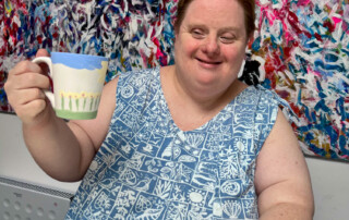 Eine Frau präsentiert ihre fertig bemalte Tasse.