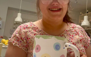 Eine Frau präsentiert ihre fertig bemalte Tasse.